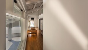 A modern interior with a wooden bench, glass walls, and a ceiling with exposed beams.