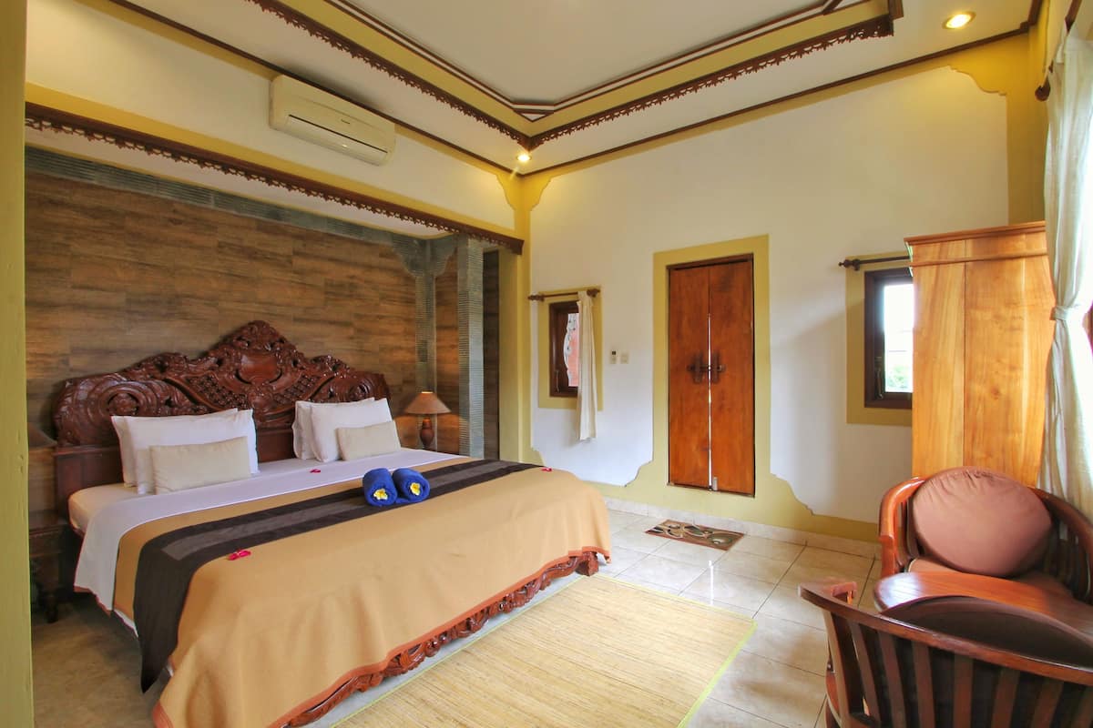 Un dormitorio con una cama grande, cabecera de madera y una silla de madera.