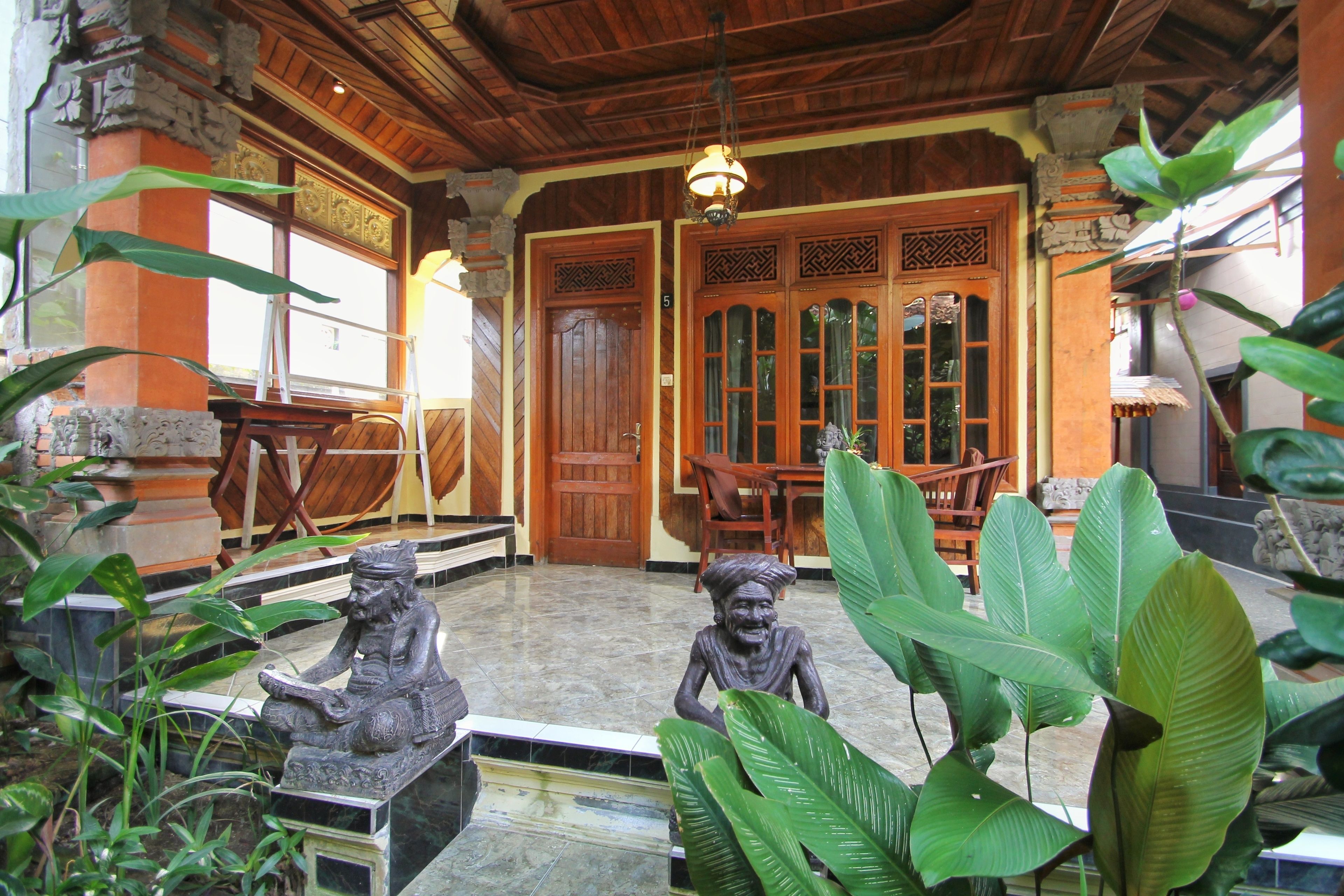 Un intérieur traditionnel en bois, agrémenté d’une statue en pierre, d’une porte en bois et d’un sol carrelé.