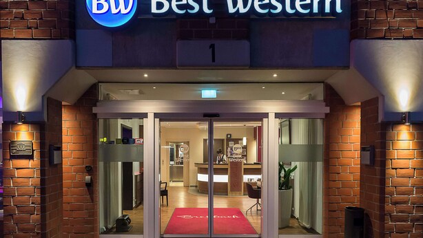 L’entrée de l’hôtel Best Western, avec son tapis rouge, ses portes en verre et son comptoir de réception visible à l’intérieur.