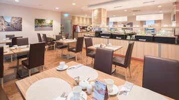 Ein modernes Café mit Holztischen und -stühlen, einer Kaffeebar und Kunstwerken an den Wänden.
