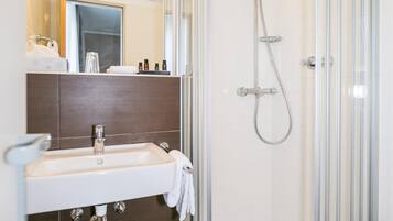 Ein modernes Badezimmer mit einer Duschkabine, einem Waschbecken mit Handtuch und einem Spiegel darüber.