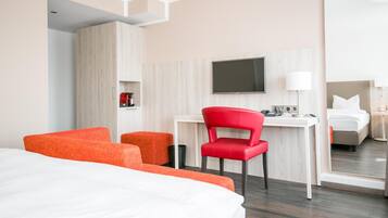 Ein Hotelzimmer mit Bett, Schreibtisch, Stuhl, Fernseher und Spiegel.