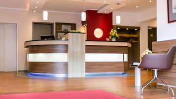 Ein Hotel-Empfangsbereich mit rotem Teppich, einer Rezeption und einer Sitzecke.