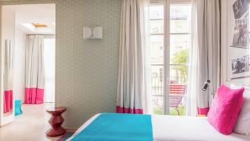 Una habitación de hotel con cama, una mesita, un espejo y una ventana con cortinas.