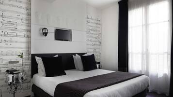 Quarto de hotel com uma cama grande, televisão de tela plana na parede e uma janela com cortinas finas.