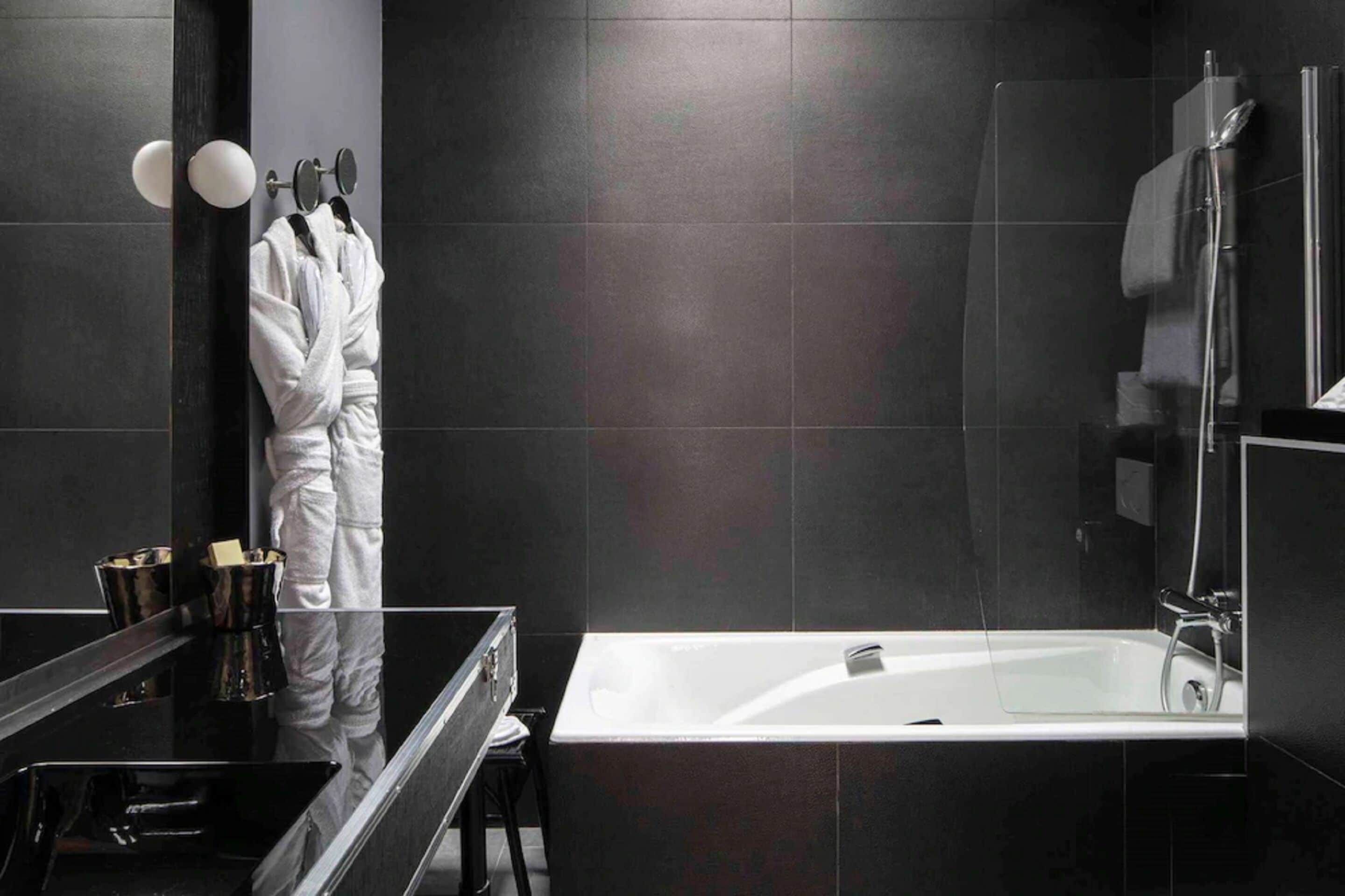 A modern bathroom with a large bathtub, a glass shower enclosure, and a vanity with a mirror and towel rack.