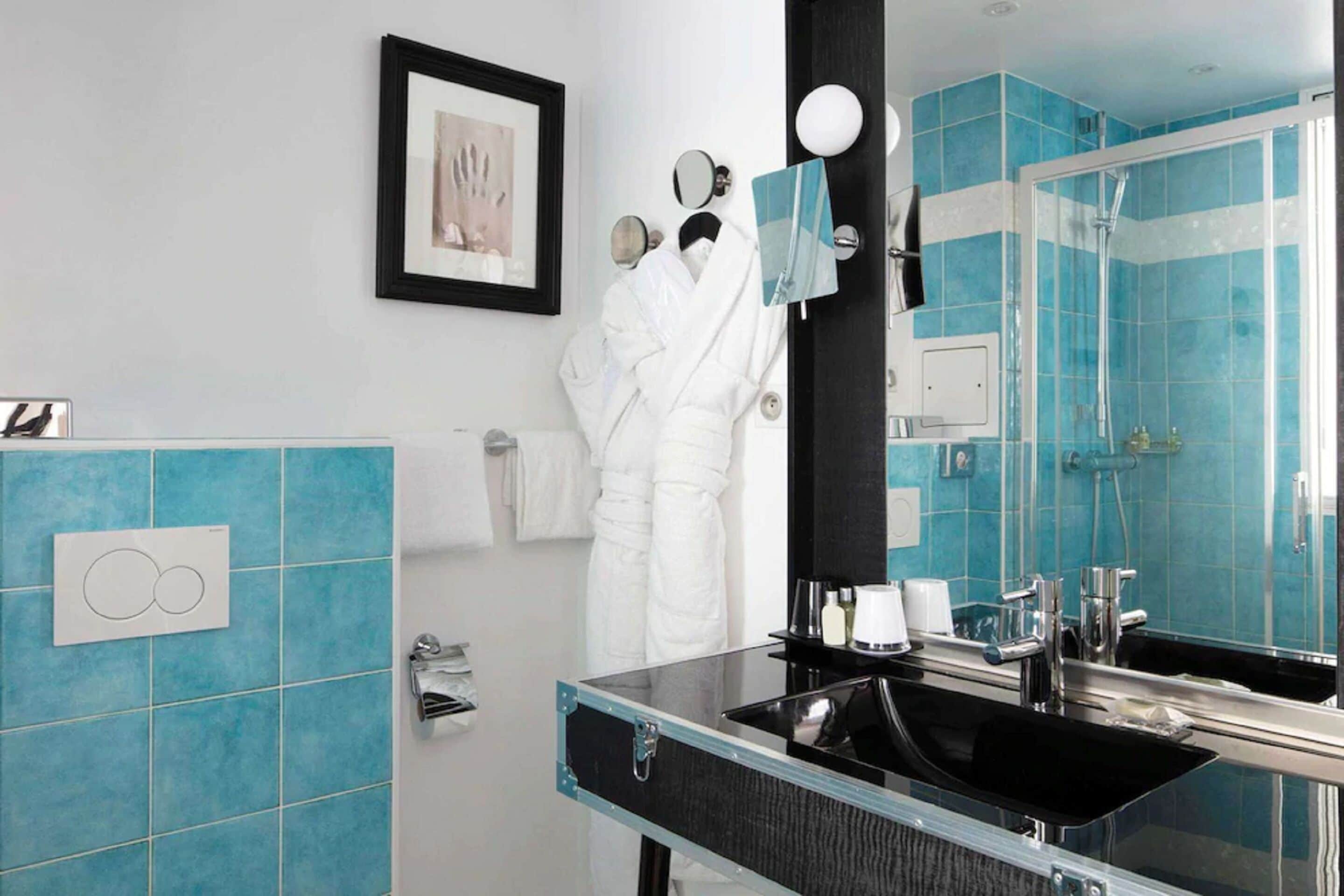 Un baño moderno con lavamanos de vidrio, un espejo grande y una zona de ducha.