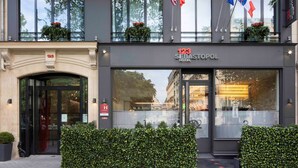 The exterior of the 123 Sebastopol Hotel with a modern facade, large windows, and flags.