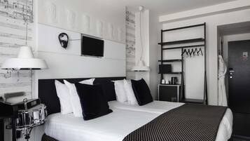 Habitación de hotel con una cama grande, dos mesitas de noche, un escritorio con lámpara, un televisor de pantalla plana y un armario.