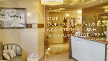 Zona de recepción de hotel con diseño moderno, mostrador de recepción y un área de estar con sofá y sillones.