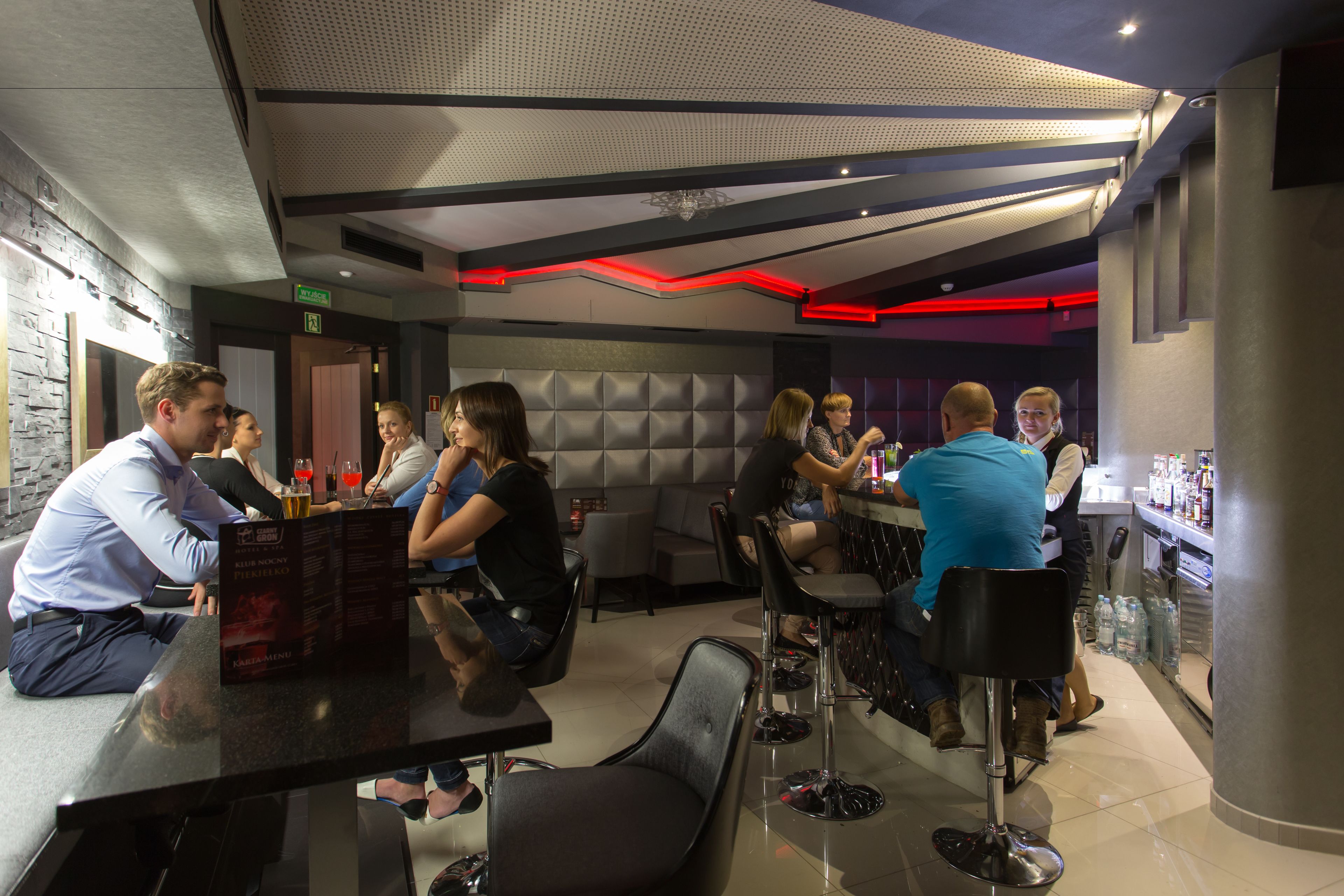 A modern bar area with seating and a bar counter, featuring a menu board and a variety of seating options.