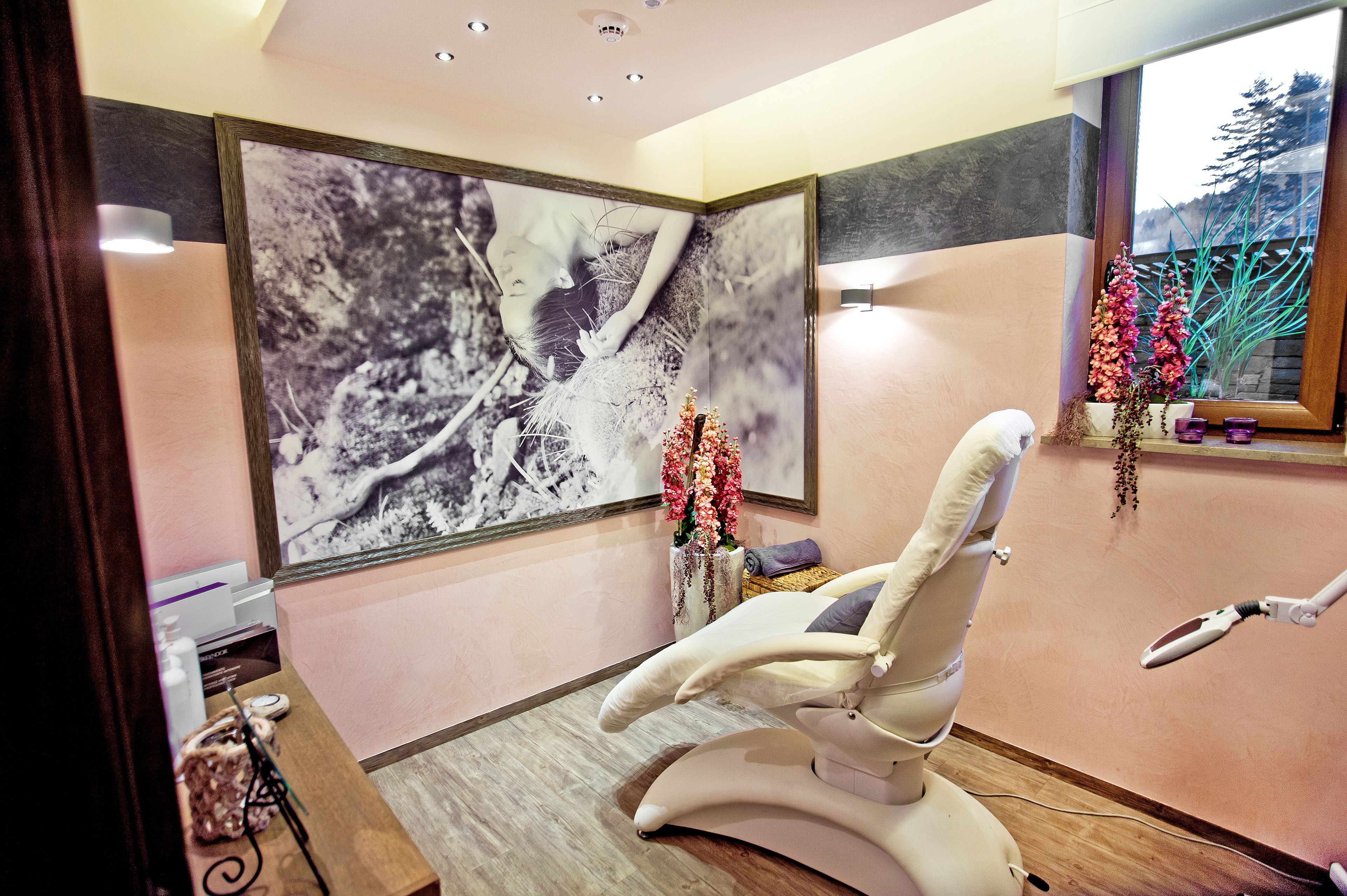 Una clínica dental moderna con un sillón dental reclinable, una fotografía grande en blanco y negro en la pared y una ventana con vistas a árboles.