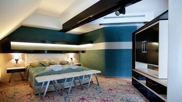 Habitación de hotel moderna con cama, banco, televisor y alfombra estampada.