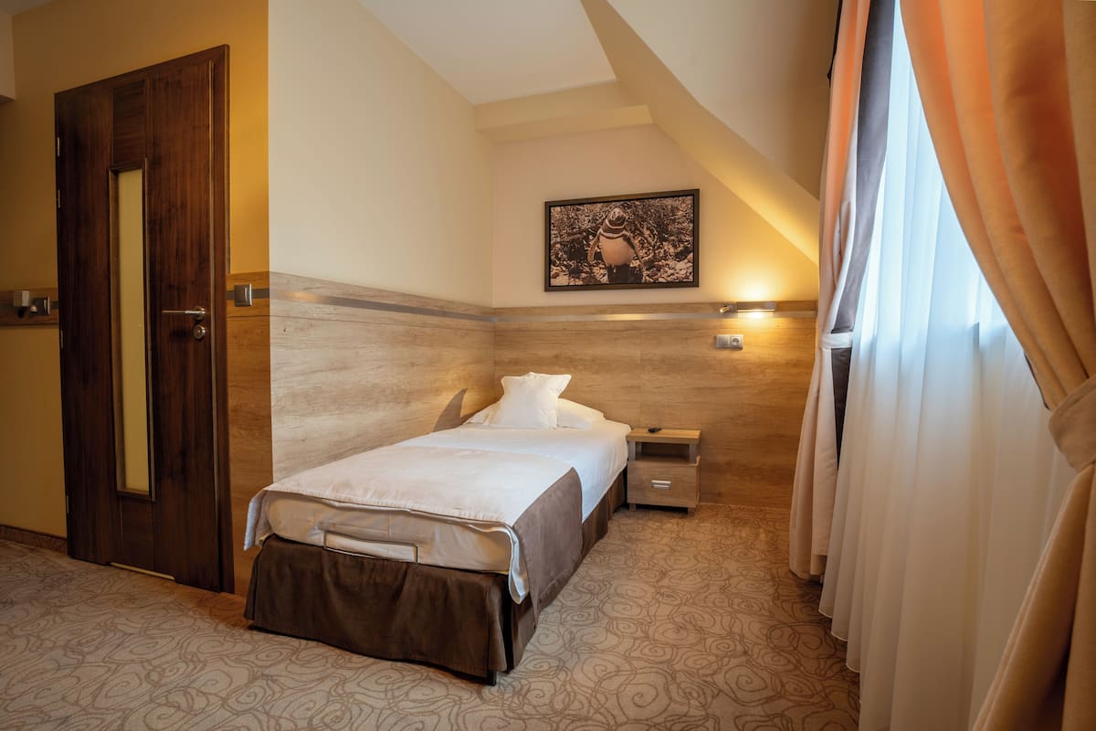 A hotel room with a bed, bedside table, and a painting on the wall.