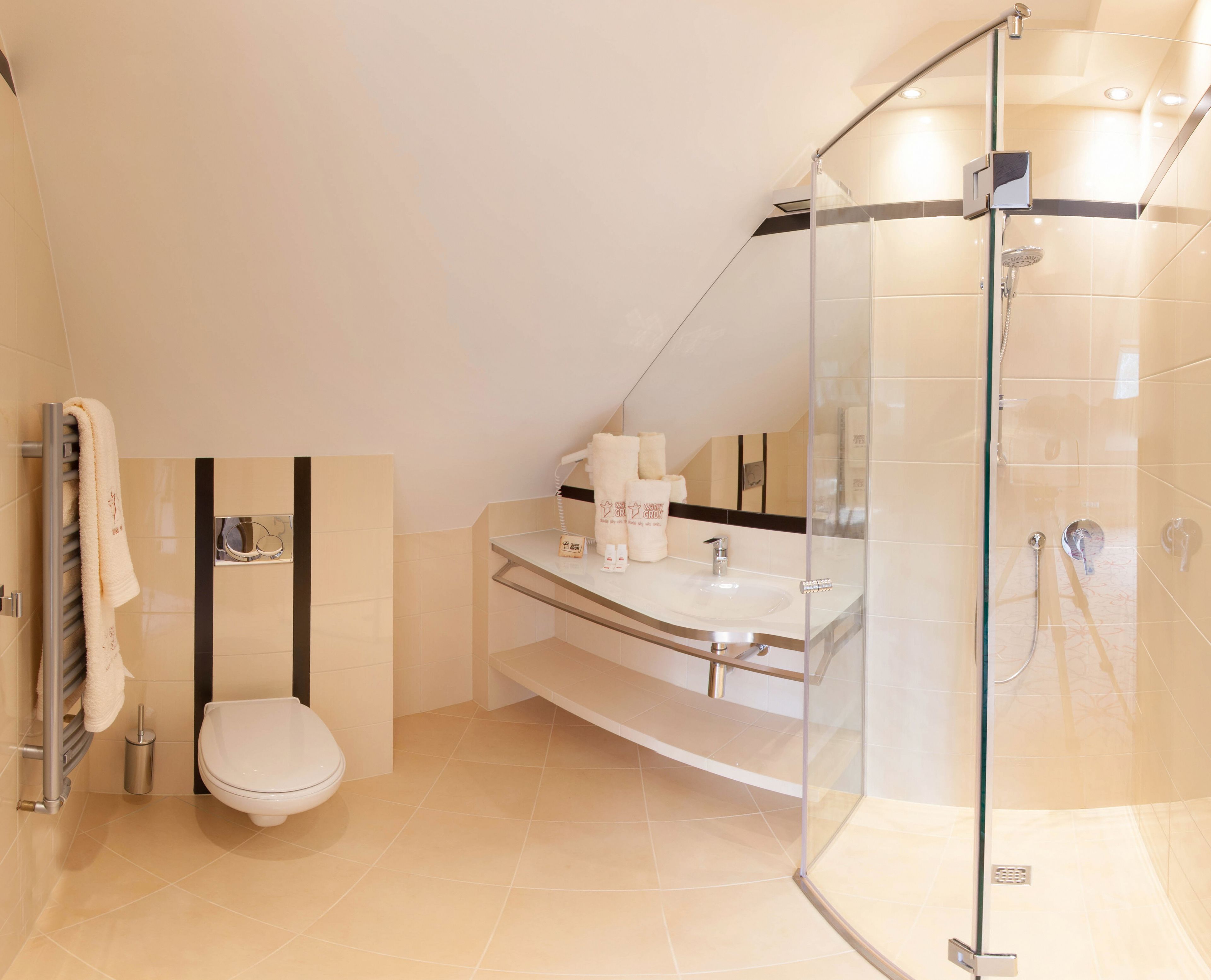 Un baño moderno con ducha de vidrio, inodoro y tocador con espejo.