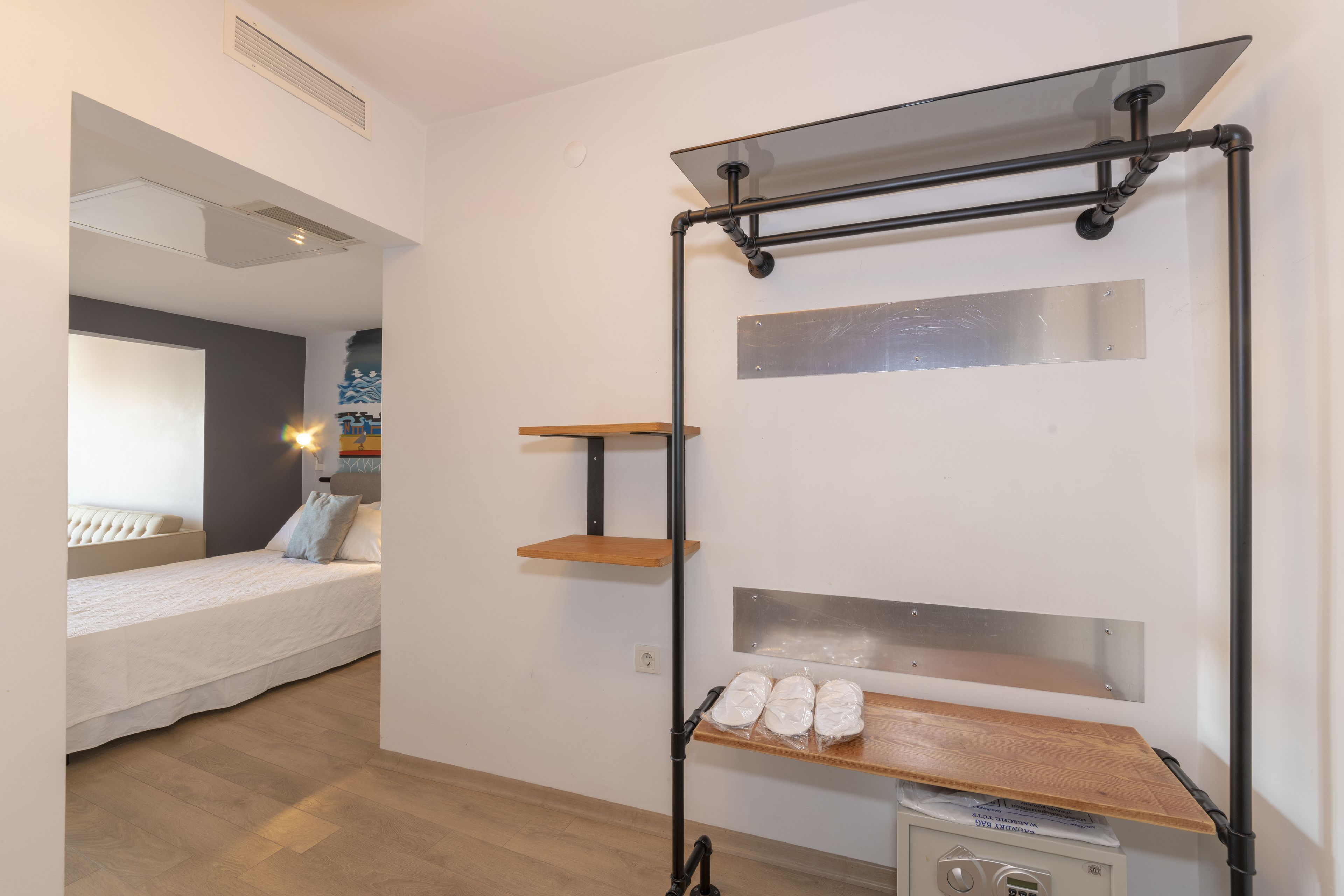 A bedroom with a bed, a wooden shelf unit, and a small table with items on it.