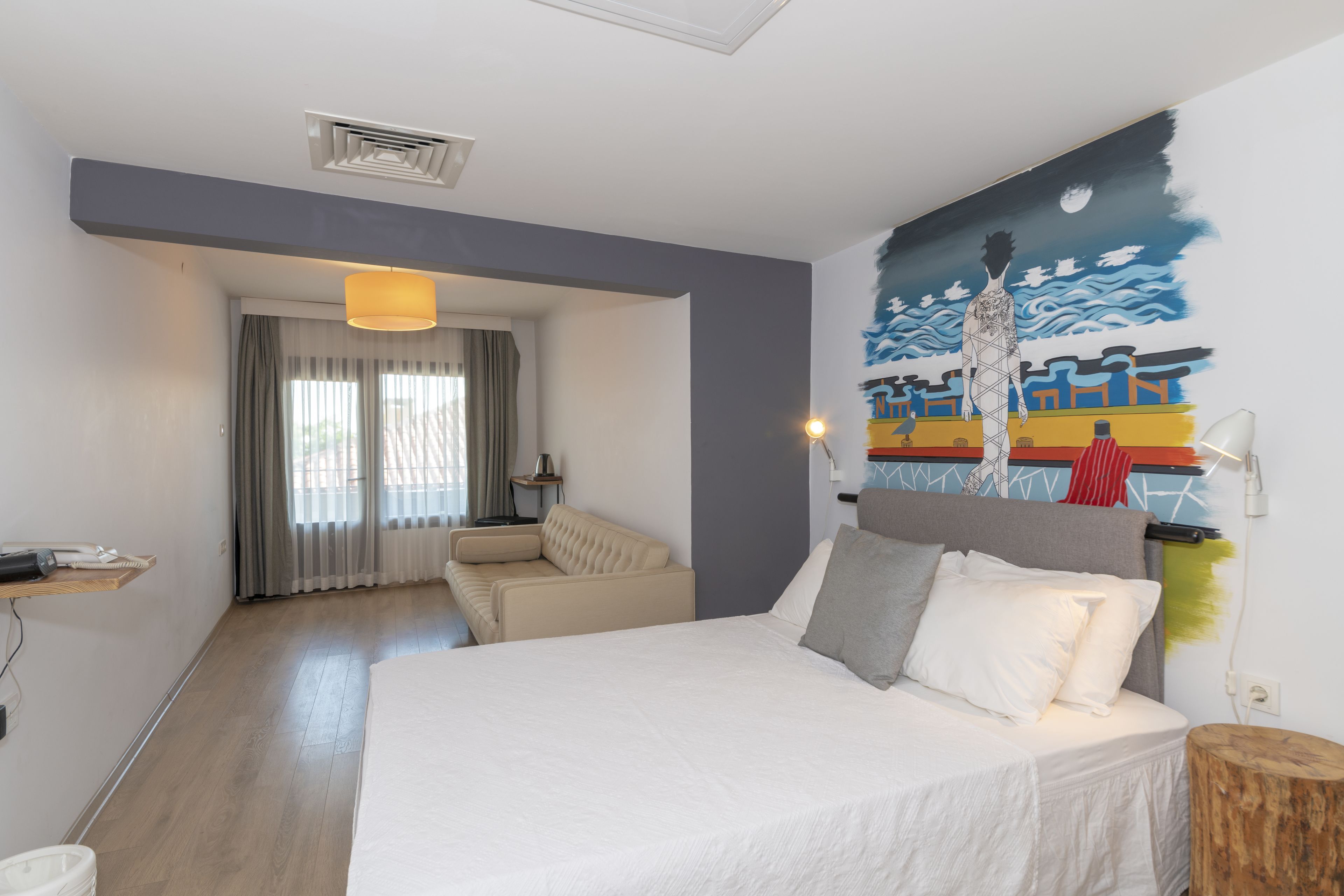 Une chambre d’hôtel moderne avec un grand lit, un canapé et un tableau au mur.