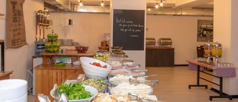 Una mesa de buffet con diversos alimentos y utensilios.