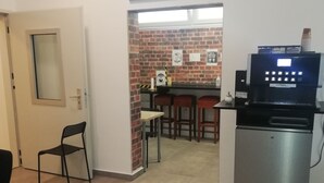 A compact kitchen with a coffee machine, a brick wall, and a cityscape painting. - The Hostel (Hamburg)