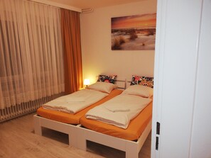 A double room with two beds, a painting on the wall, and a window with curtains. - The Hostel (Hamburg)