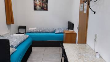 Ein kleiner, gemütlicher Raum mit Bett, Schreibtisch und Stuhl.
