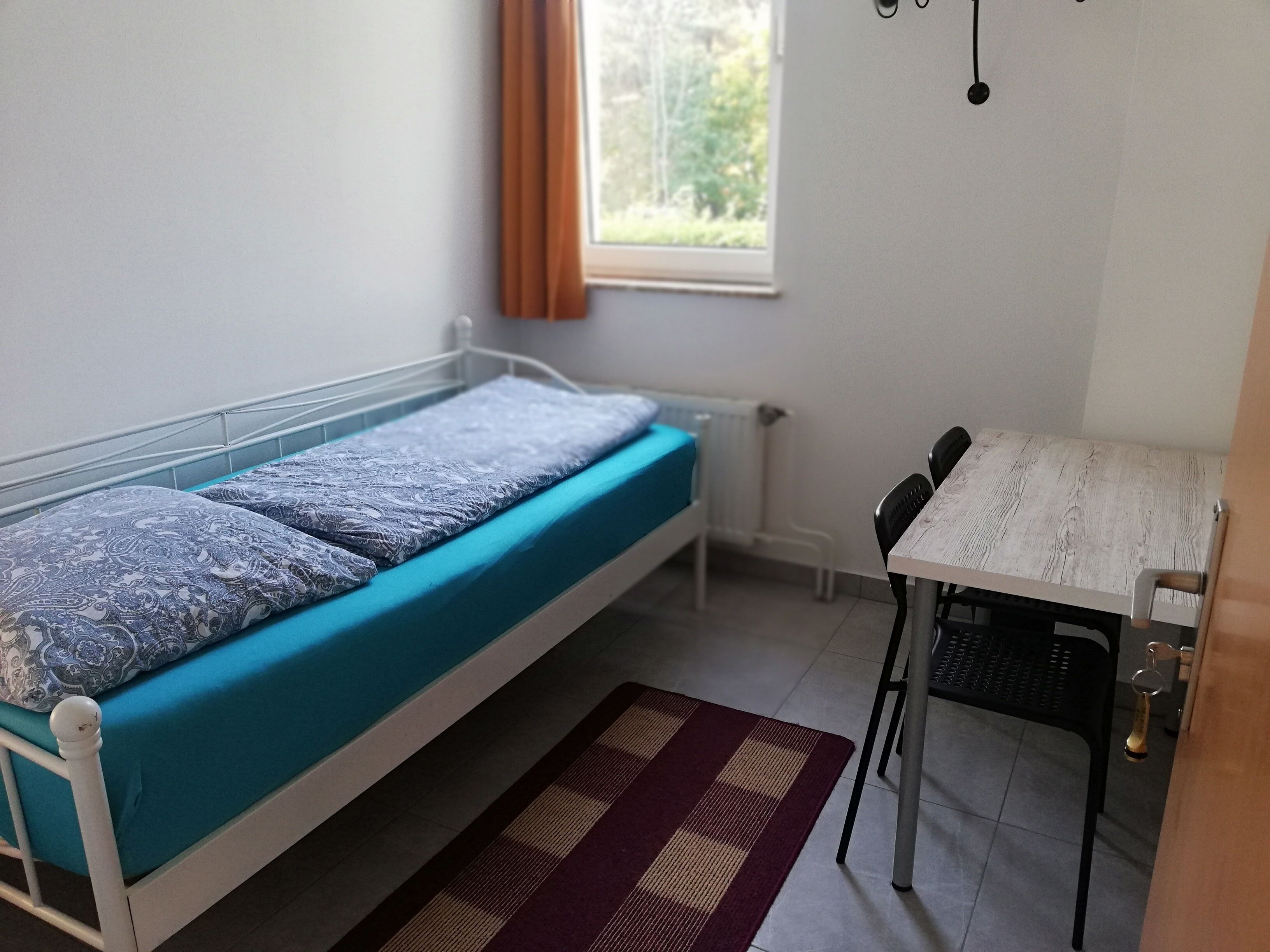 A small room with a single bed, a table, and a chair.