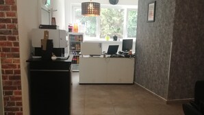 A modern kitchen with a coffee machine, a refrigerator, and a window with a view of trees. - The Hostel (Hamburg)