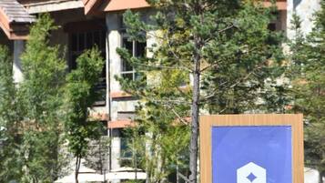 A sign for a Hyatt Regency hotel with a mountain backdrop and a garden with colorful flowers.