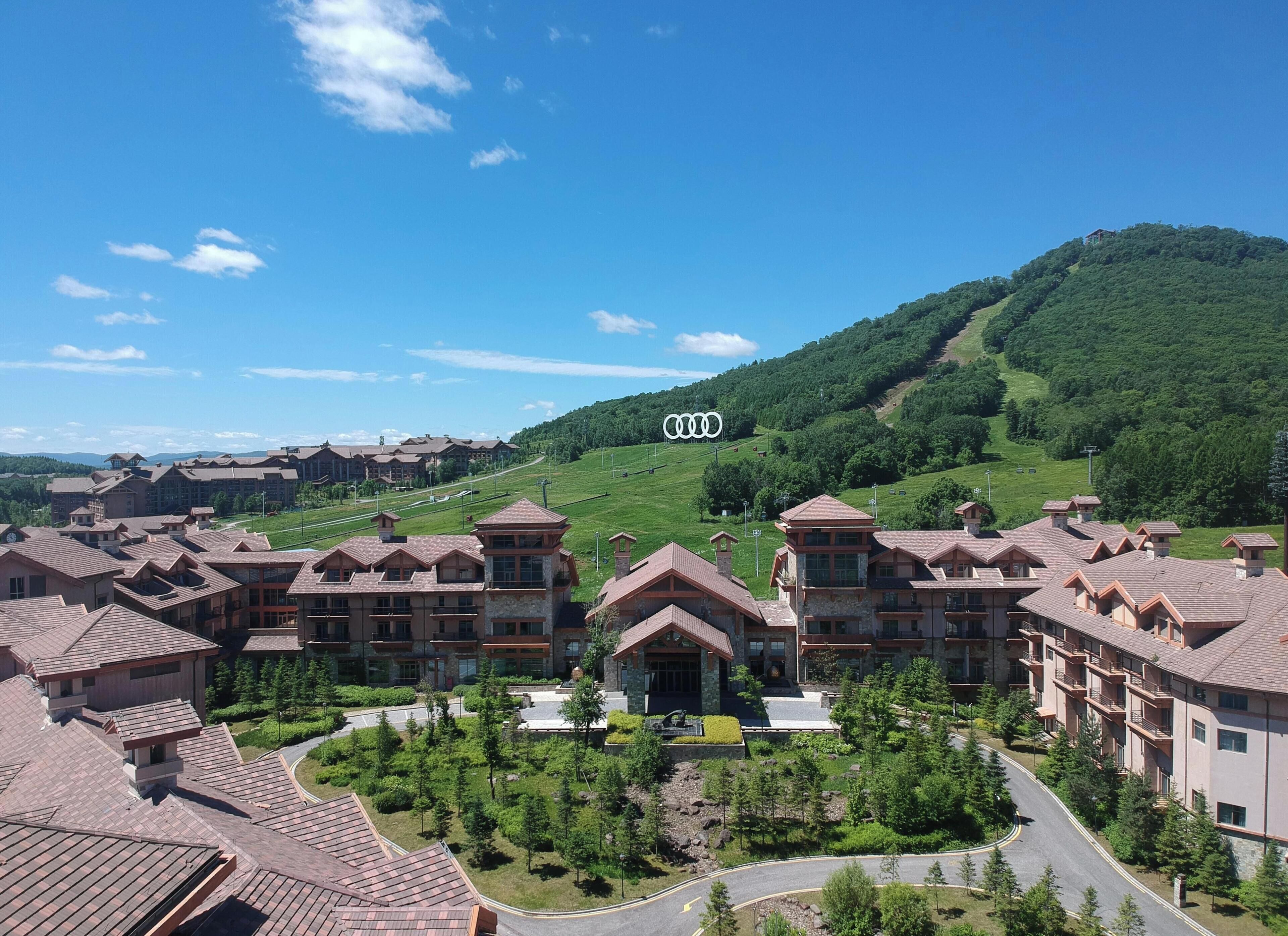 A resort with multiple buildings, a central entrance, and a hilly backdrop.