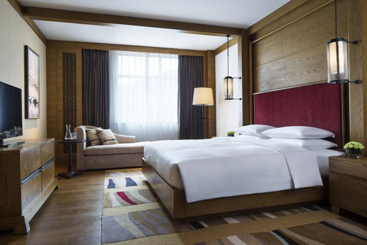 A hotel room with a large bed, a sofa, a desk, and a TV.