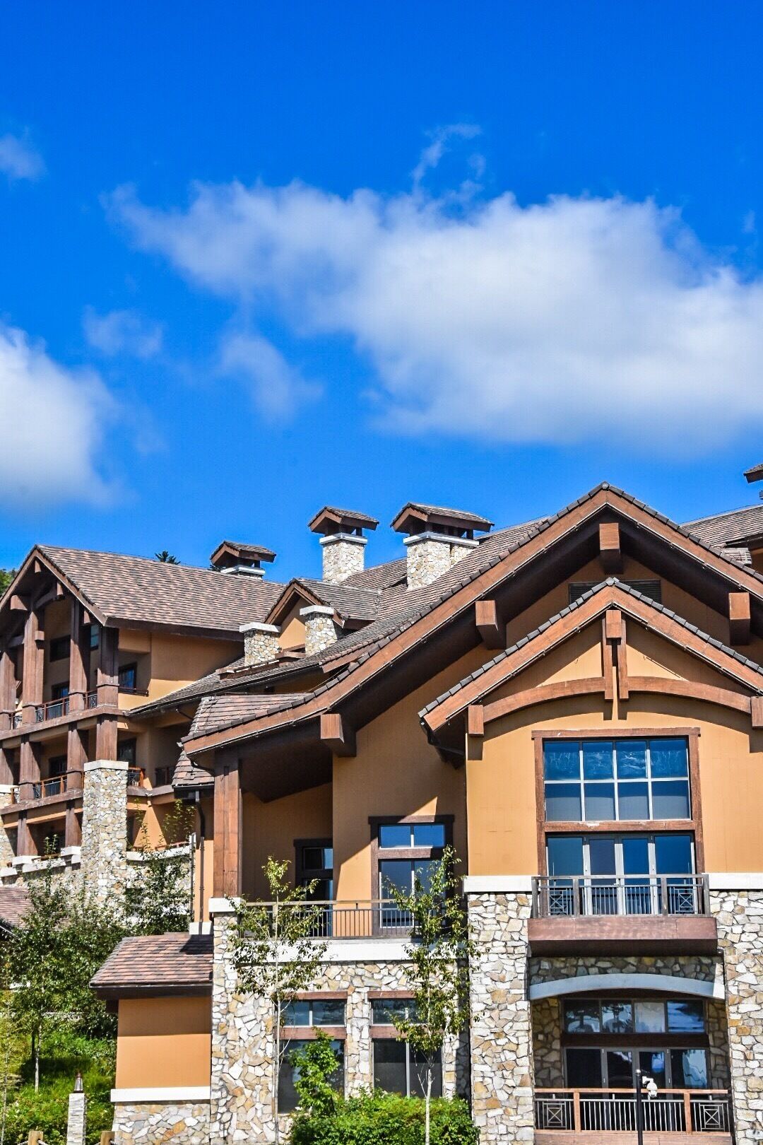 A multi-story building with stone and wood exterior, balconies, and large windows.