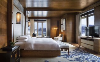 Un dormitorio amplio con una cama grande, un televisor y vistas a un paisaje nevado.