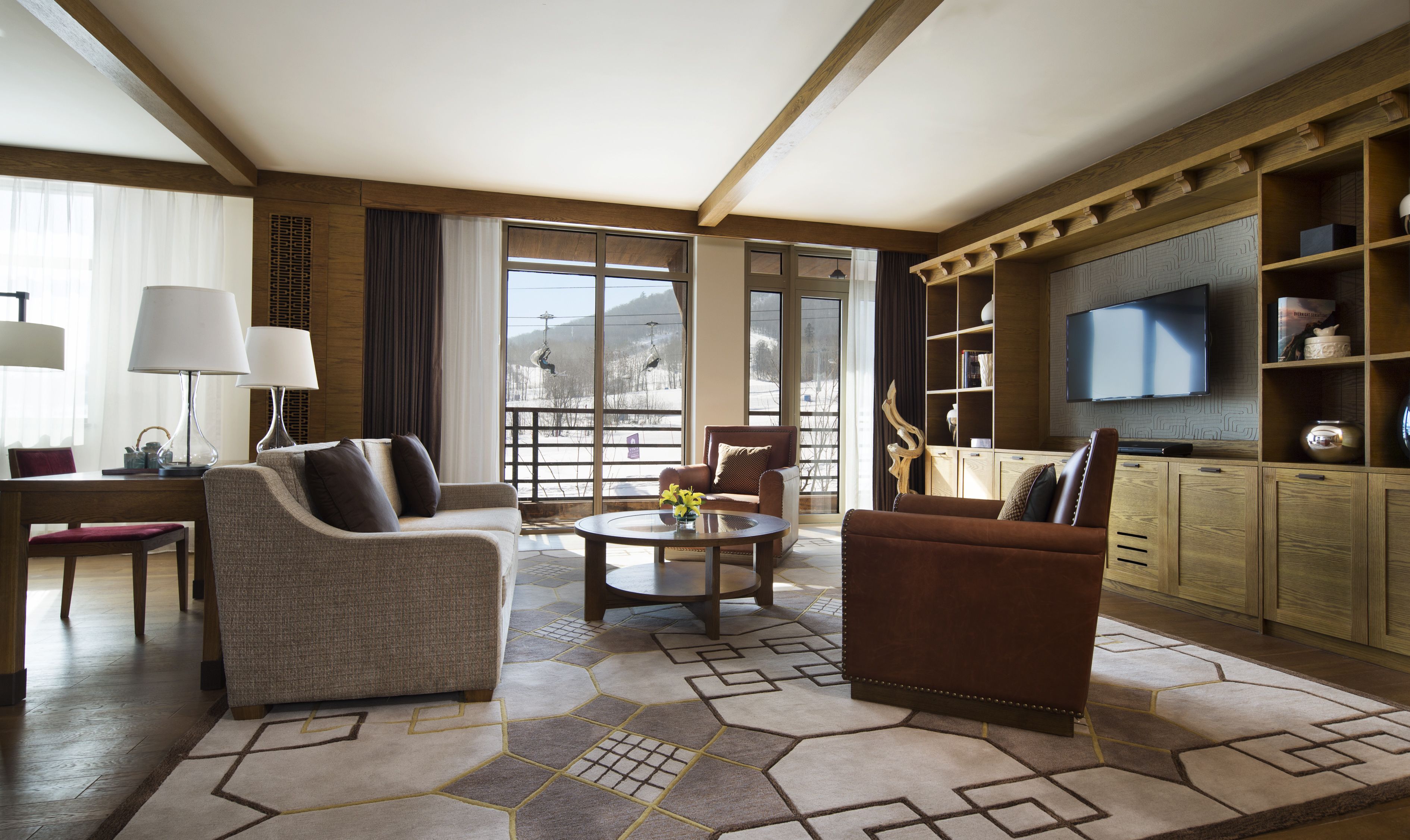 A spacious living room with a large window, a television, and a wooden cabinet.