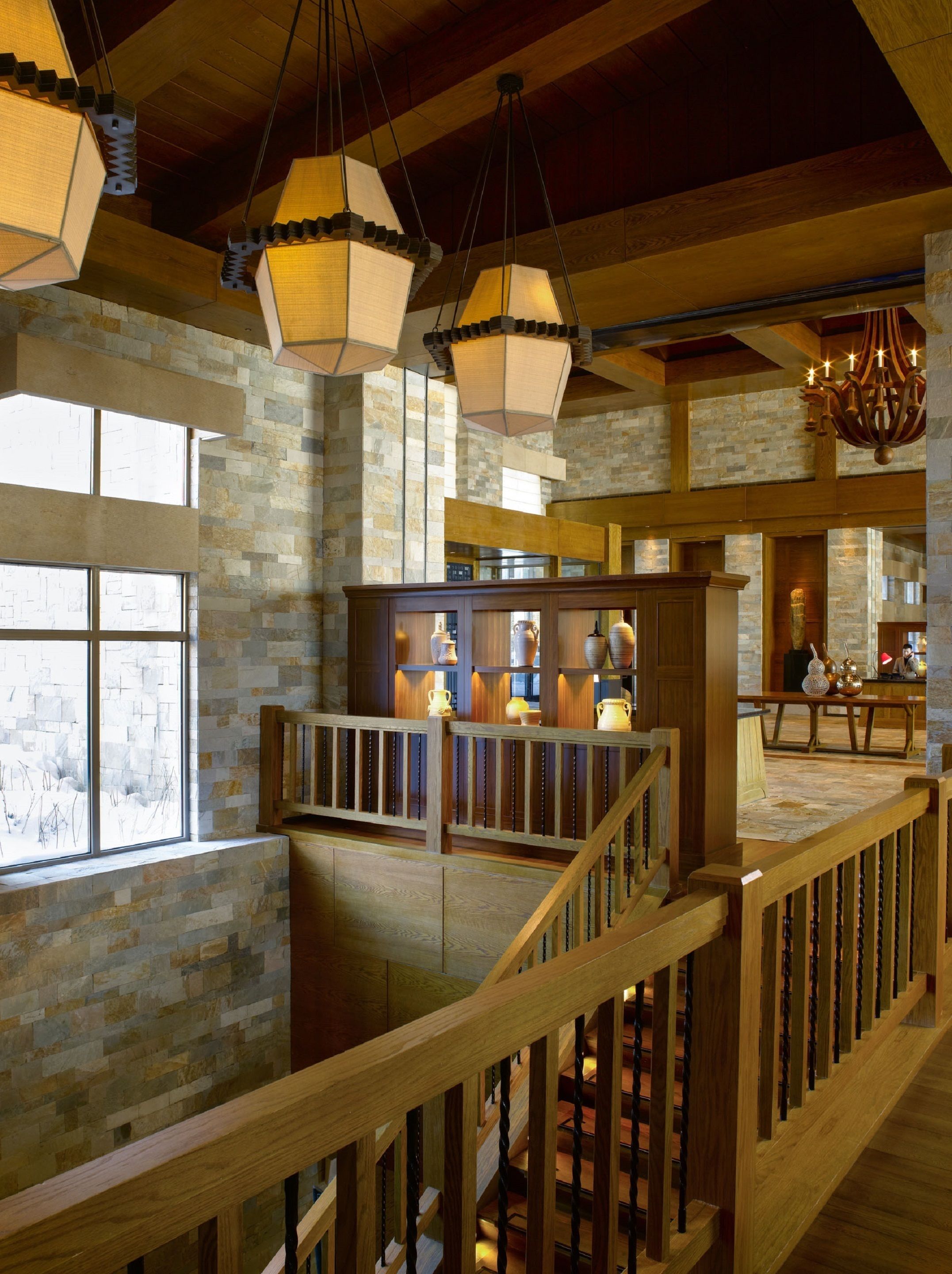 A spacious interior with a wooden staircase, stone walls, and a kitchen area with modern appliances.