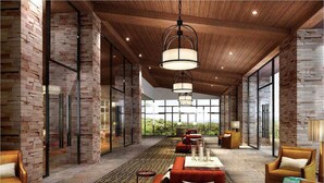 A spacious lobby with a high ceiling, exposed brick walls, and a large seating area with red sofas and armchairs. - Park Hyatt Changbaishan (Baishan)