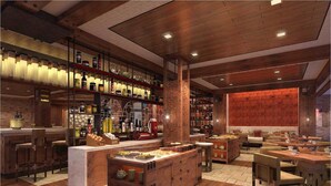 Un restaurante con suelo de madera, una isla central con asientos y estantes llenos de botellas y frascos.