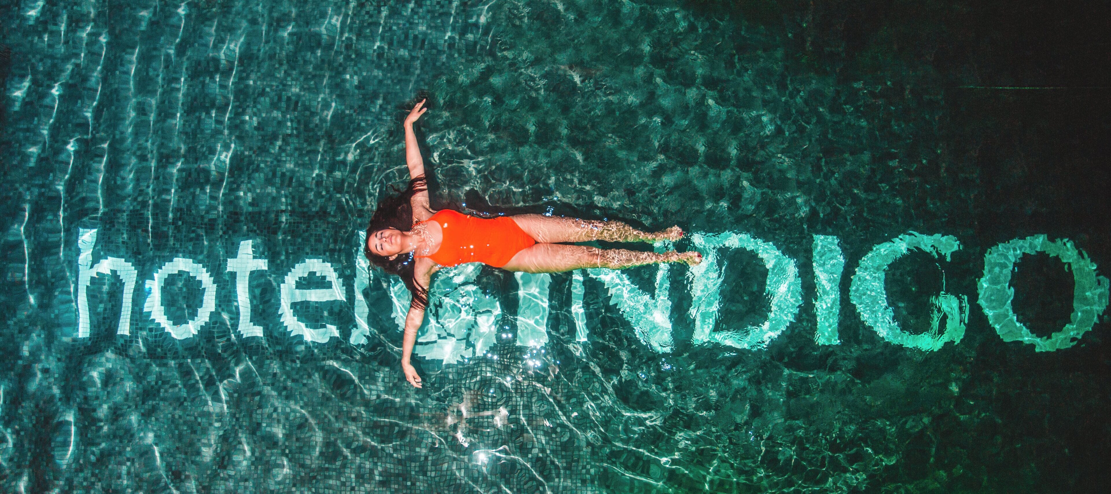 Una persona nuota in piscina, con la parola 'hotel' scritta nell'acqua.