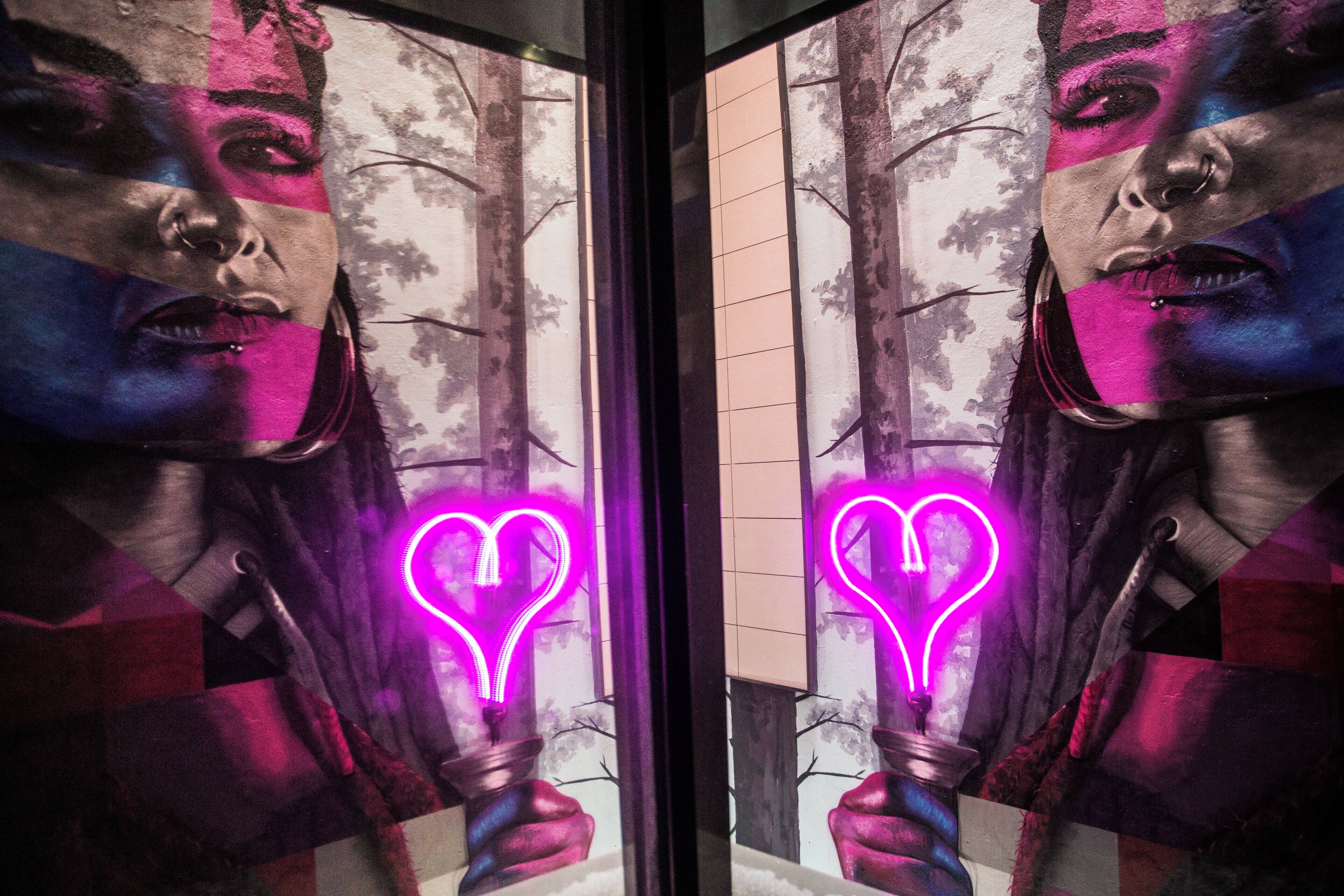 A mirror reflecting a person holding a hookah with a neon heart symbol.
