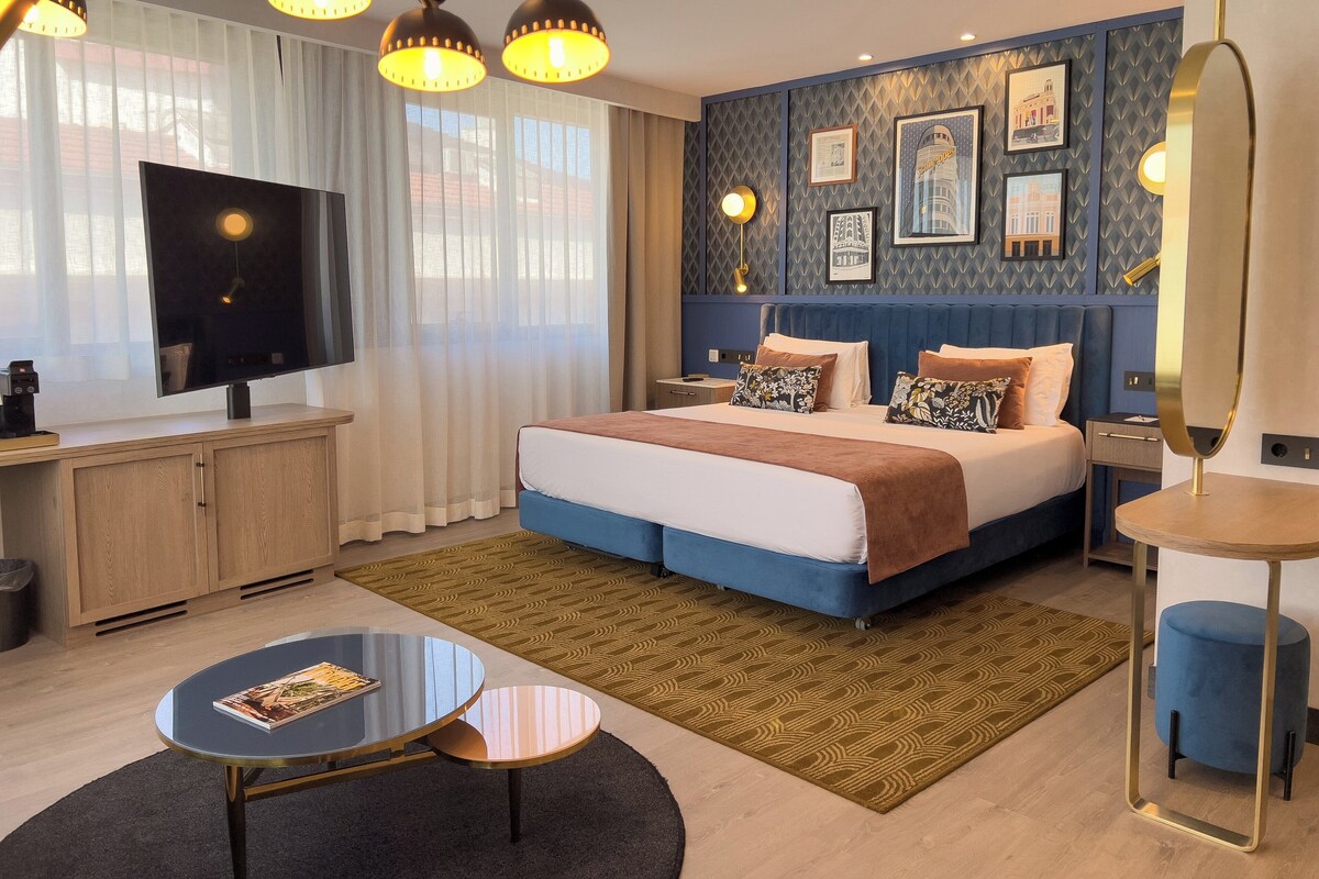 Una habitación de hotel moderna con una cama grande, un televisor y un escritorio con cafetera.