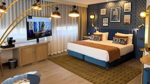 A modern hotel room with a large bed, a desk with a computer, and a TV displaying a cityscape. - Hotel Indigo Madrid - Gran Via by IHG (Madrid)