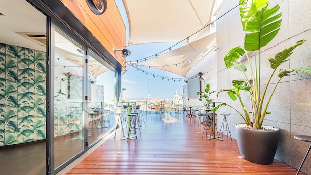 An outdoor deck with wooden flooring, potted plants, and string lights. - Hotel Indigo Madrid - Gran Via by IHG (Madrid)