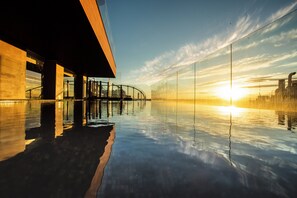 Un bâtiment moderne doté d’une façade en verre qui reflète le ciel et offre une vue dégagée sur l’horizon.