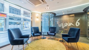 A modern hotel lobby with two blue armchairs, a small round table, and a yellow rug. - Hotel Indigo Madrid - Gran Via by IHG (Madrid)
