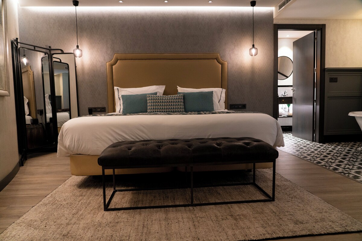 Un dormitorio moderno con una cama grande, un banco y un espejo.