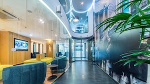 A modern lobby with a curved glass wall, seating areas, and a television screen. - Hotel Indigo Madrid - Gran Via by IHG (Madrid)