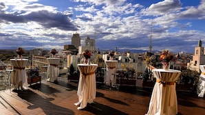 A rooftop terrace with tables set up for dining, overlooking a cityscape with buildings and a clear sky. - Hotel Indigo Madrid - Gran Via by IHG (Madrid)