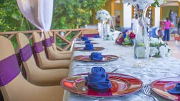 A table set with red and clear plates, blue napkins, and white flowers.