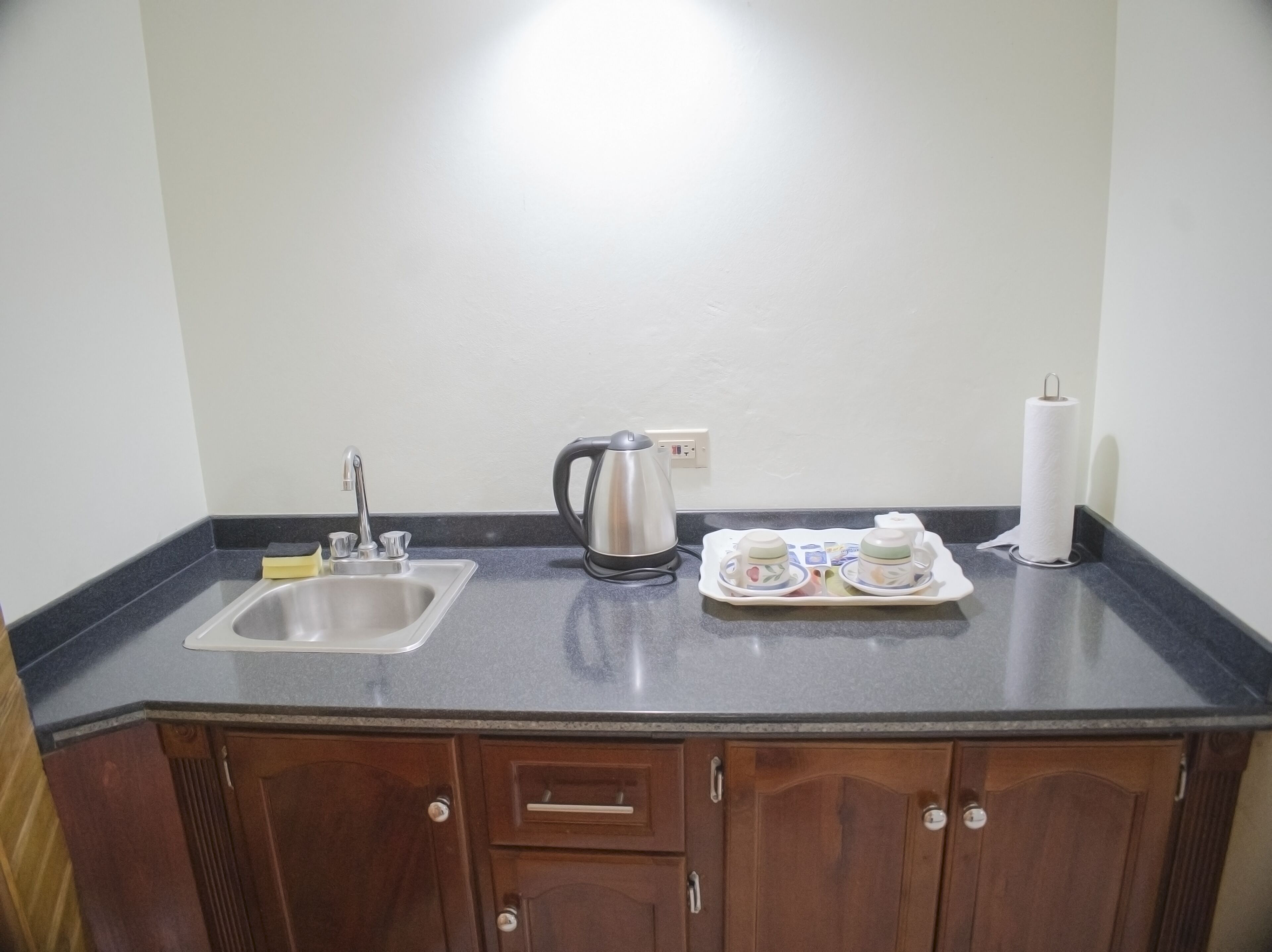 Una cocina con lavamanos, tetera y juego de té.