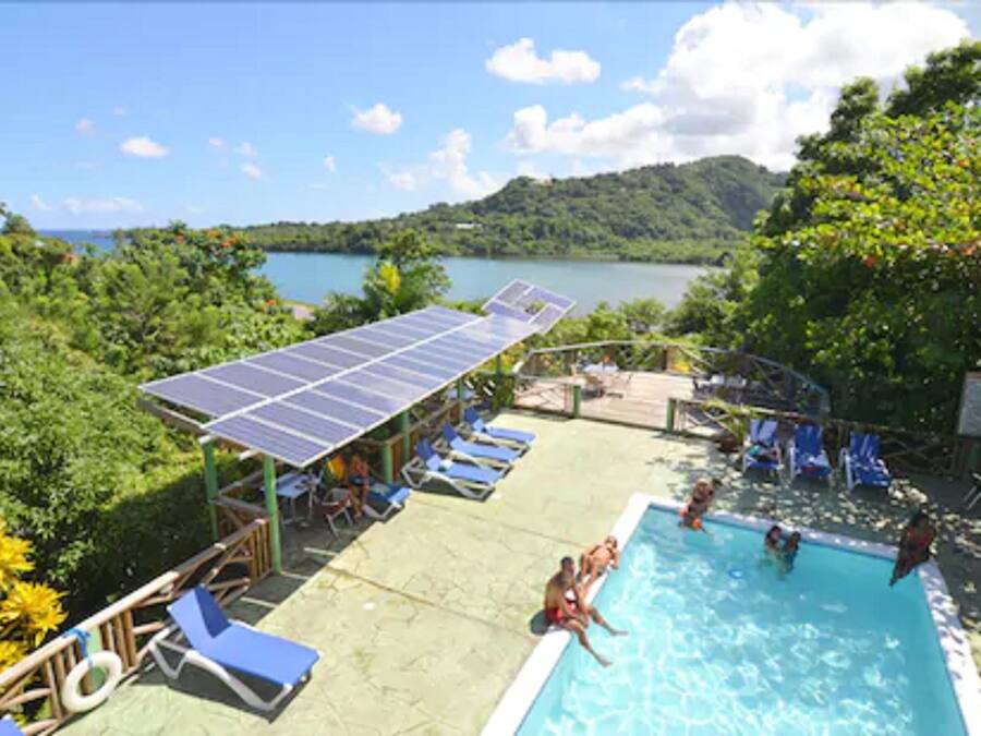 Ein Swimmingpool mit Solaranlage, Liegestühlen und Blick auf einen See und Hügel.